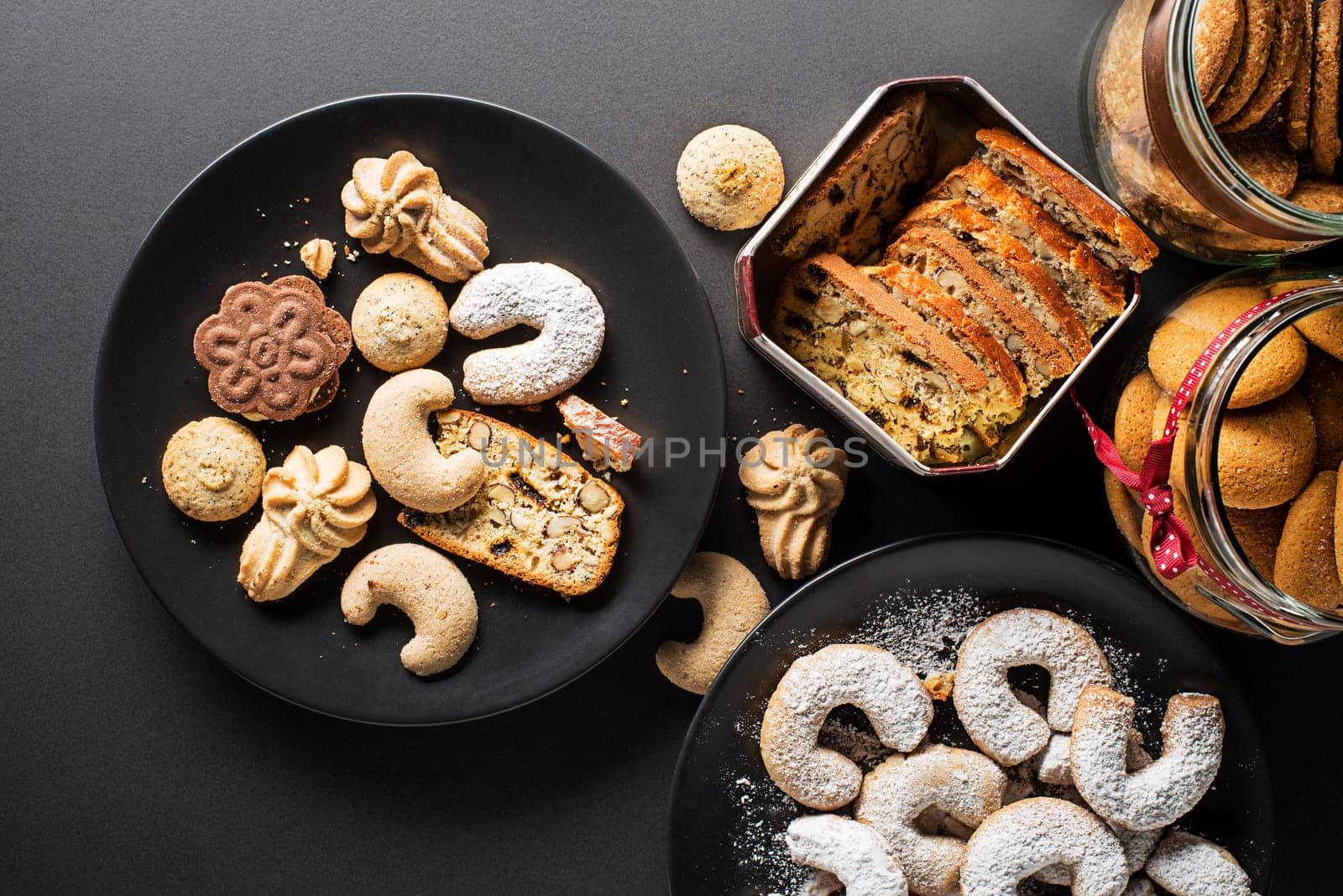 Tasty homemade sugar cookies and biscuits of all shapes and sizes on black table background