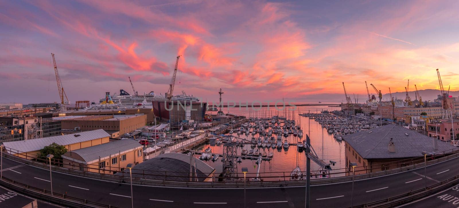 Genoa, Italy - 06 26 2021: Genoa Port Yacht Club at sunset with boats and cranes.