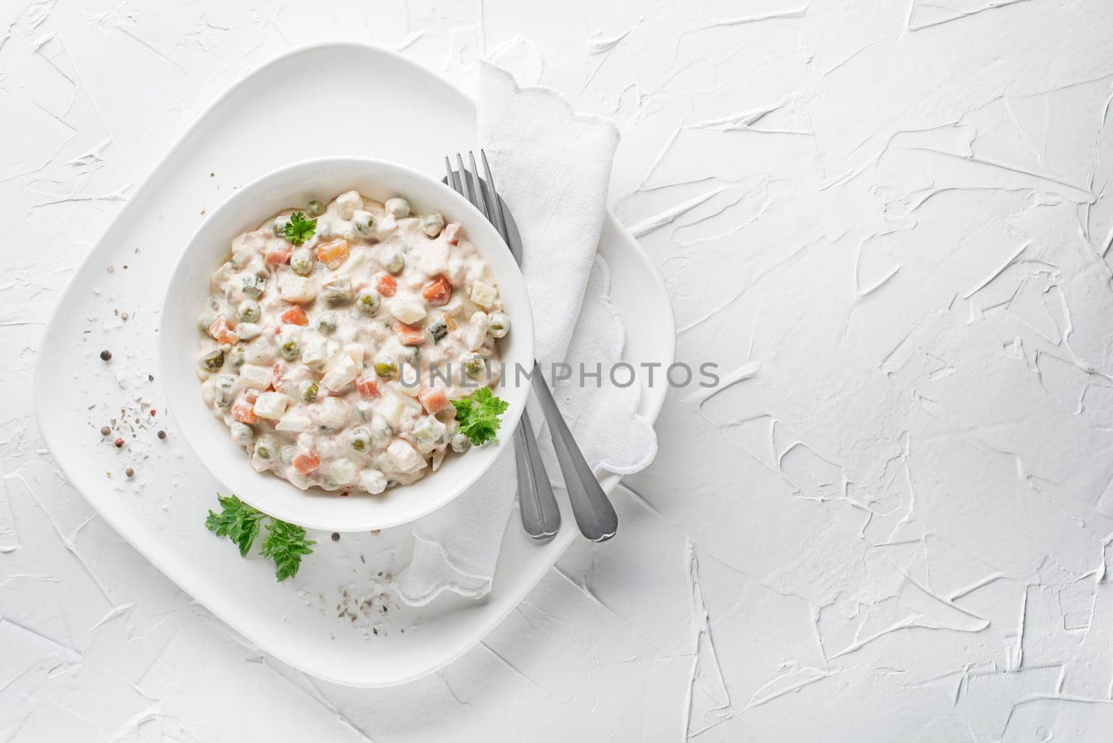 Bowl of russian salad olivier french salad with vegetables and egg dressed with mayonnaise on white table