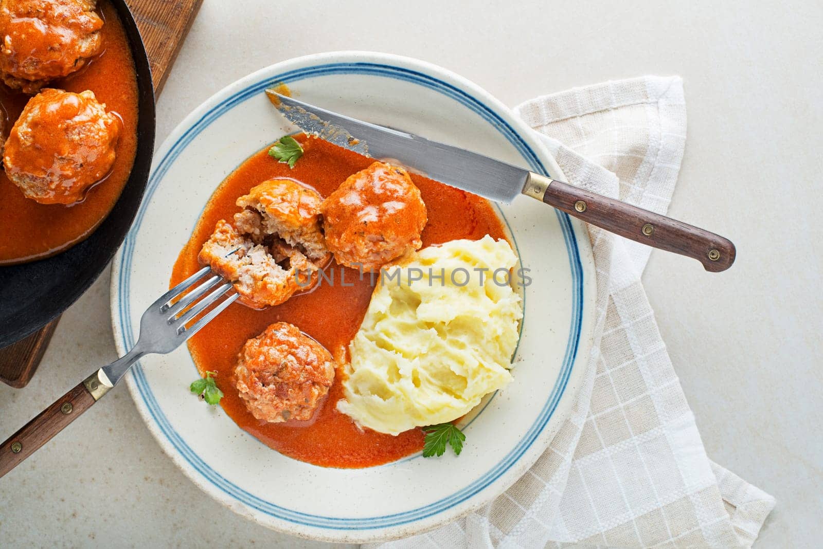 Fried meatballs braised in tomato sauce served with mashed potatoes on white table. Eating Beef roasted meatballs in tomato sauce.