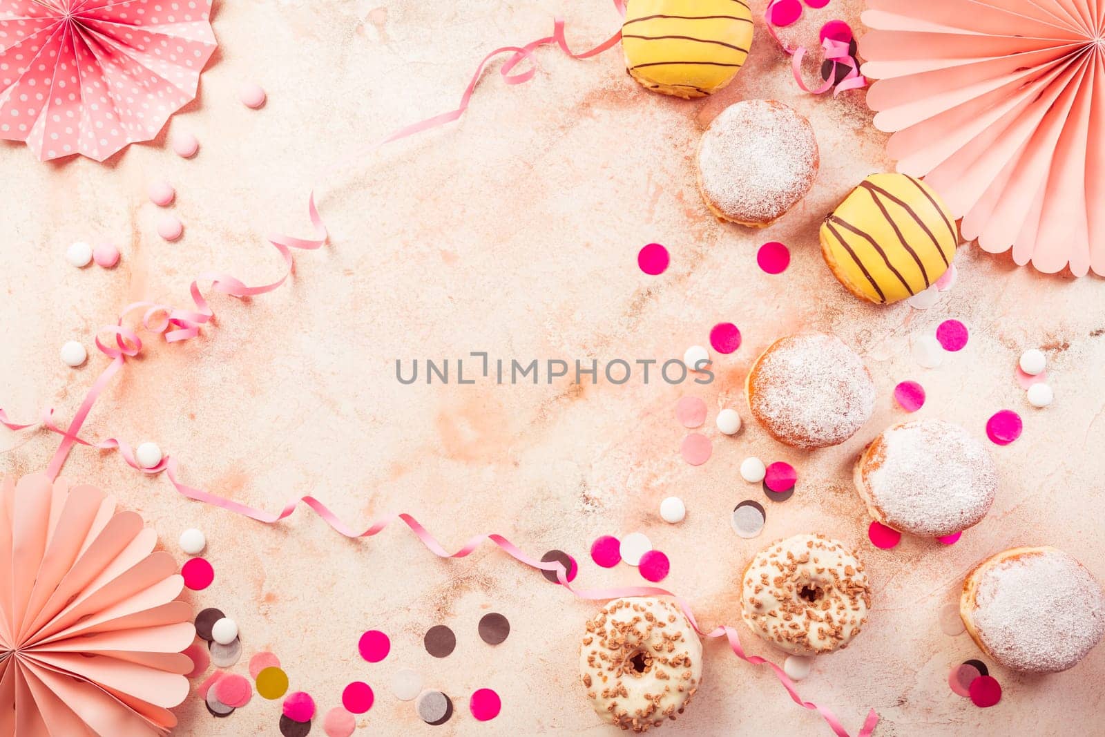 Traditional Berliner for carnival and party. German Krapfen or donuts with streamers and confetti. Colorful carnival or birthday image