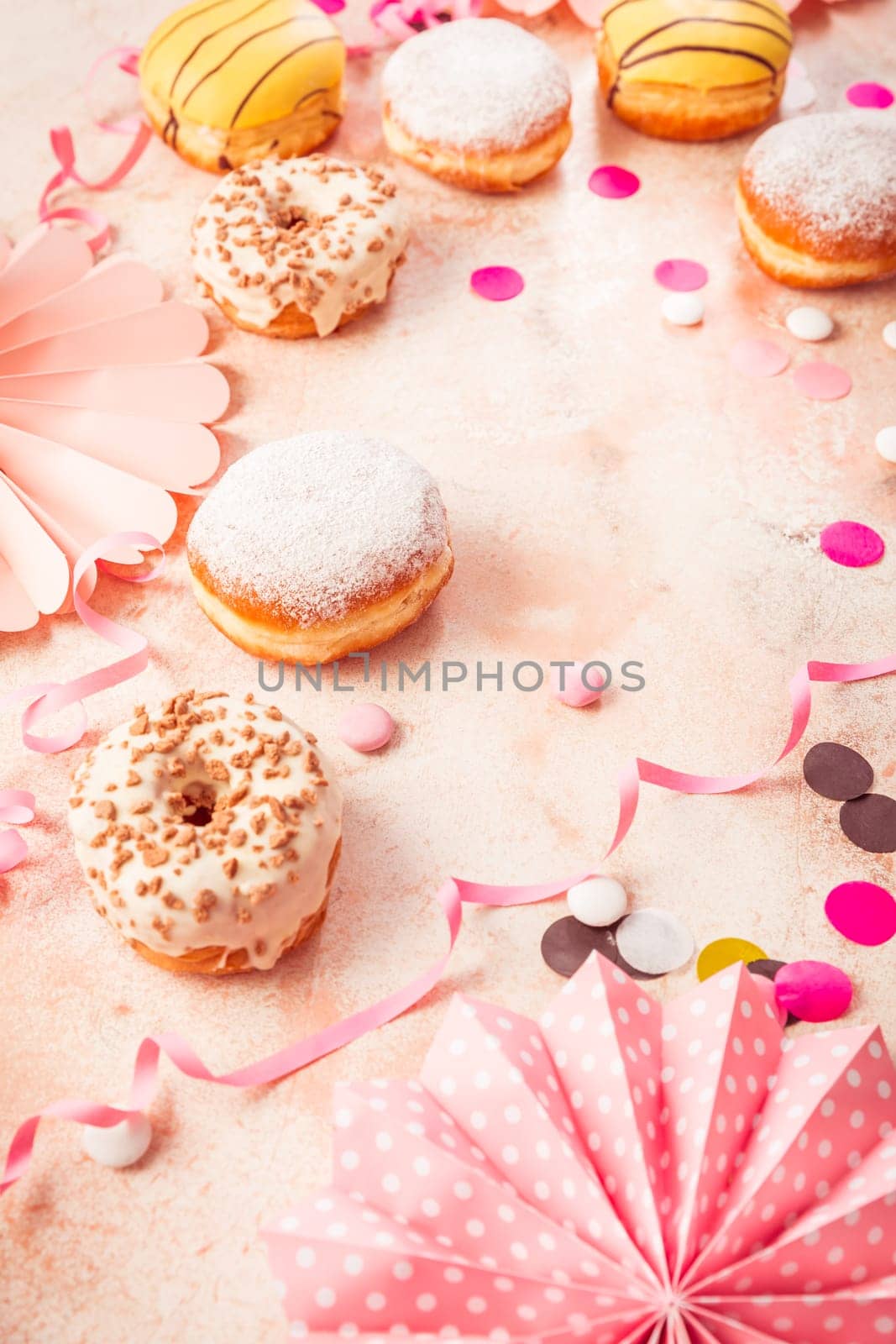 Traditional Berliner for carnival and party. German Krapfen or donuts with streamers and confetti. Colorful carnival or birthday image