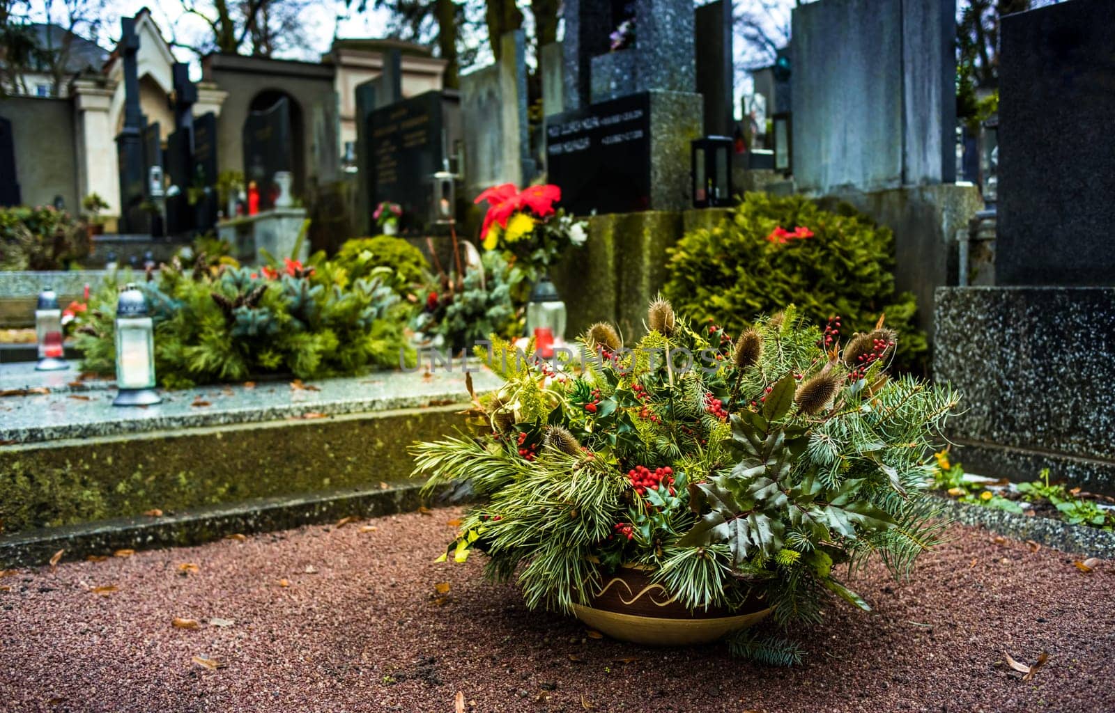 Flower arrangement and funeral wreath at grave in cemetery. Tombstones and a chapel in the public cemetery. Grief and paying respect for dead person. T