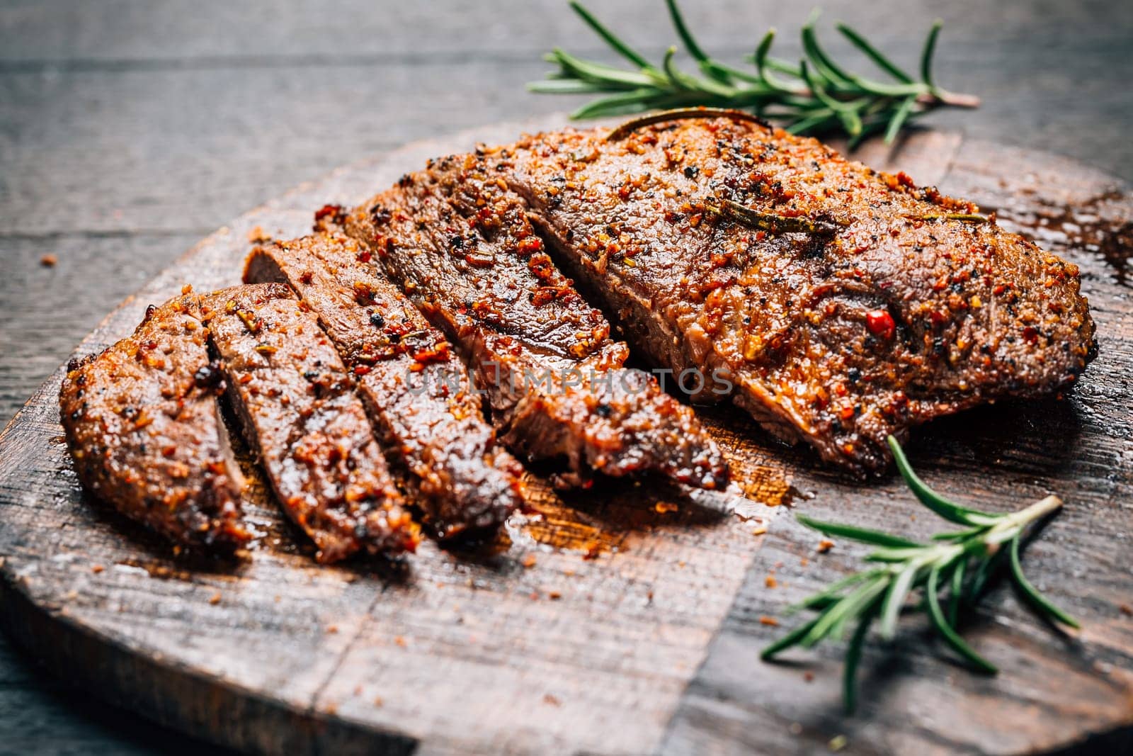Grilled beef steak with spices on cutting board on wooden background