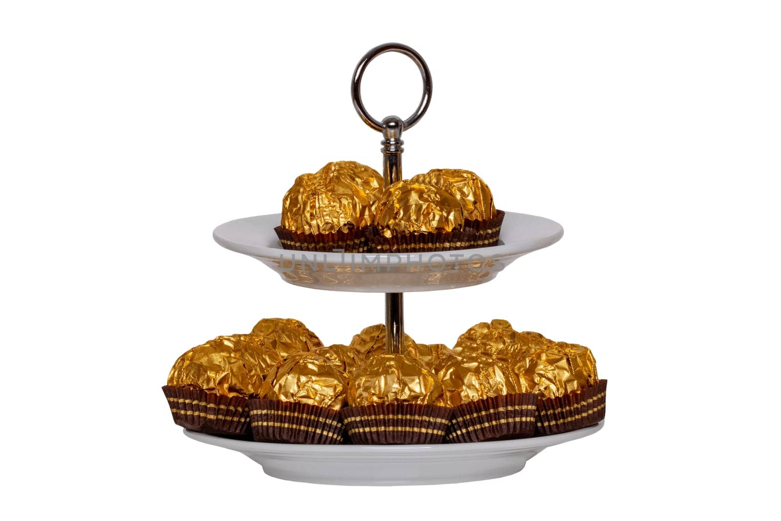 Pastries, desserts and sweets. Chocolate candies wrapped in golden foil on a two-storey etagere isolated on a white background. Clipping path. Decoration element for greeting card, poster or invitation. Macro.