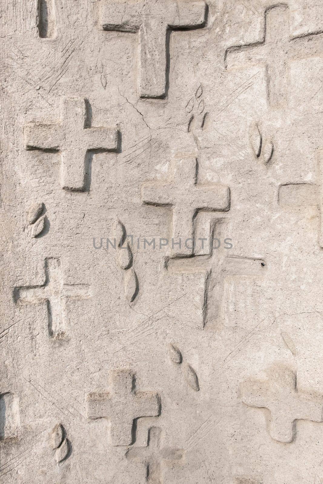 Abstract background of engraved and relief crosses on stone wall. Religious symbol.