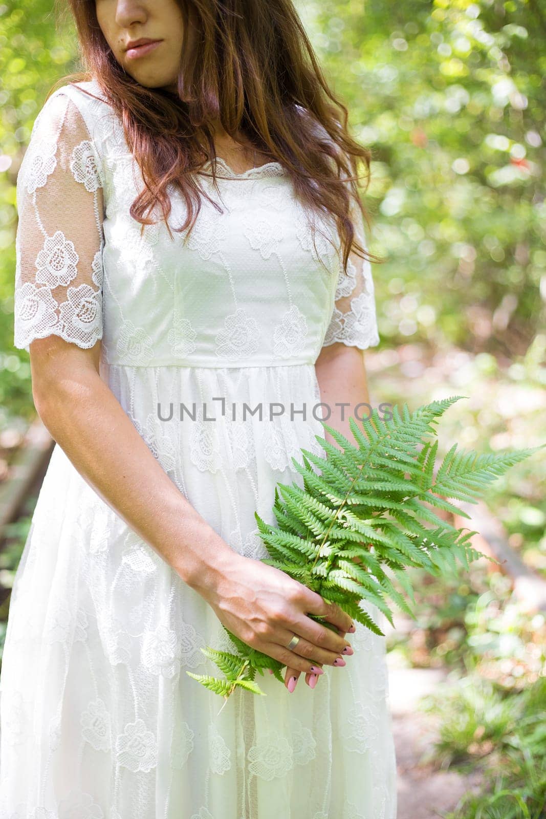 beautiful girl in a white dress holding a fern