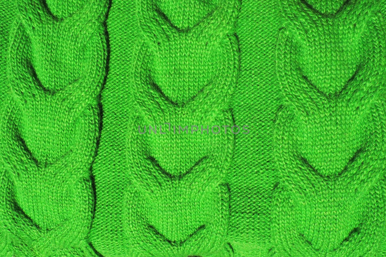 Pigtail knit. Pattern of knitted fabric. Green yarn. Front and back loops. Knitted pattern close up. Knitting as a hobby. Women's needlework. Knit for warm sweaters