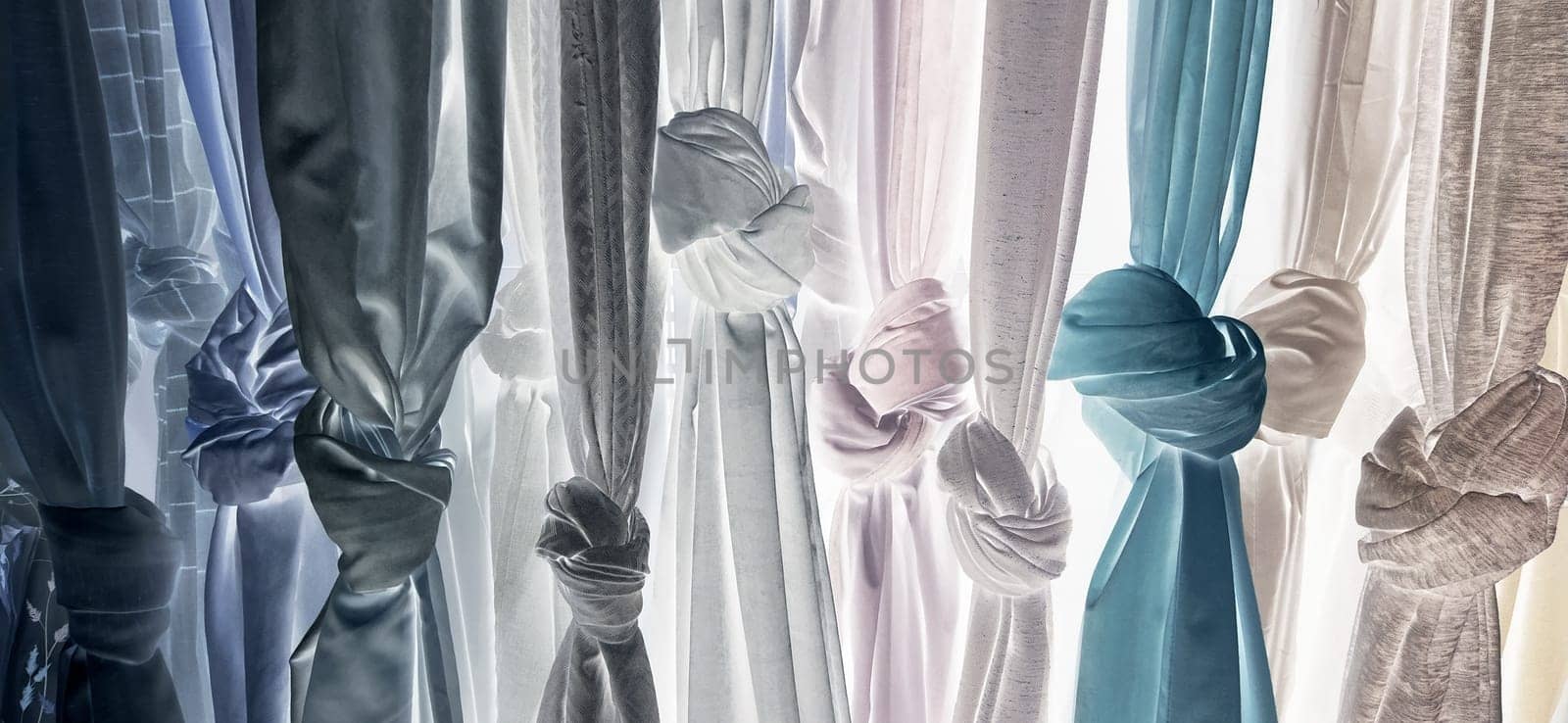 Curtain and fabric for drapery and interior decoration. Samples of fabrics in the store are hung vertically and tied in knots. Curtains in the showcase. Negative, inverted photo
