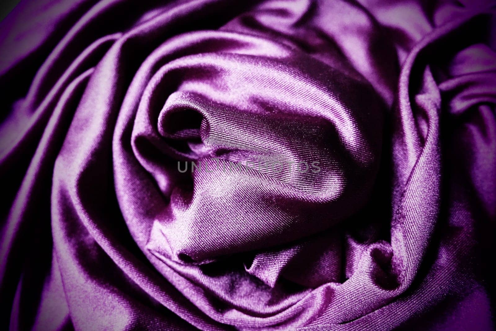 Velour fabric, similar to silk. Textiles in a folds, beautiful waves, twisted into a circle. Purple, pink, magenta shades on the drapery. Sewing material for dresses, furniture upholstery, curtains
