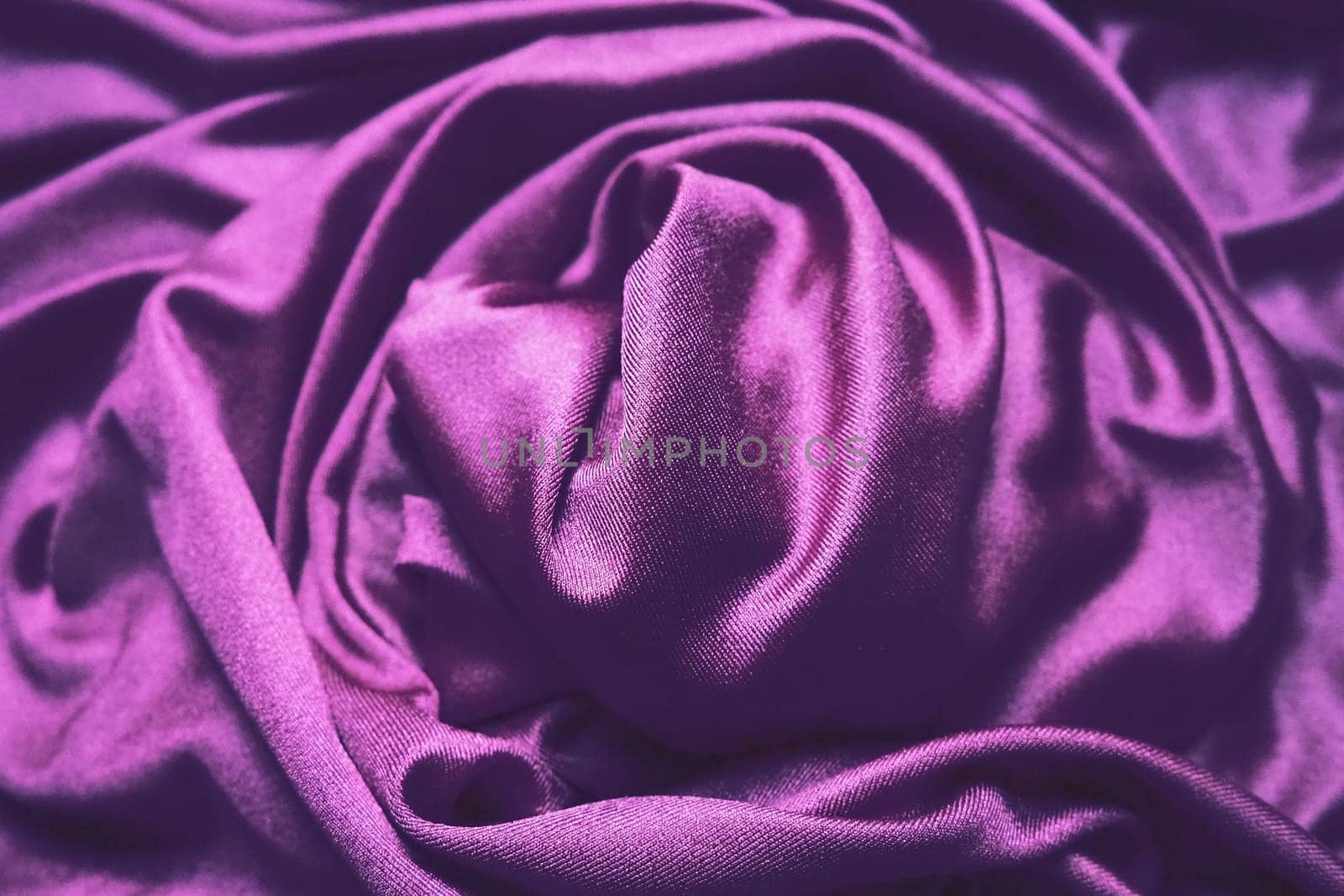 Velour fabric, similar to silk. Textiles in a folds, beautiful waves, twisted into a circle. Purple, pink, magenta shades on the drapery. Sewing material for dresses, furniture upholstery, curtains