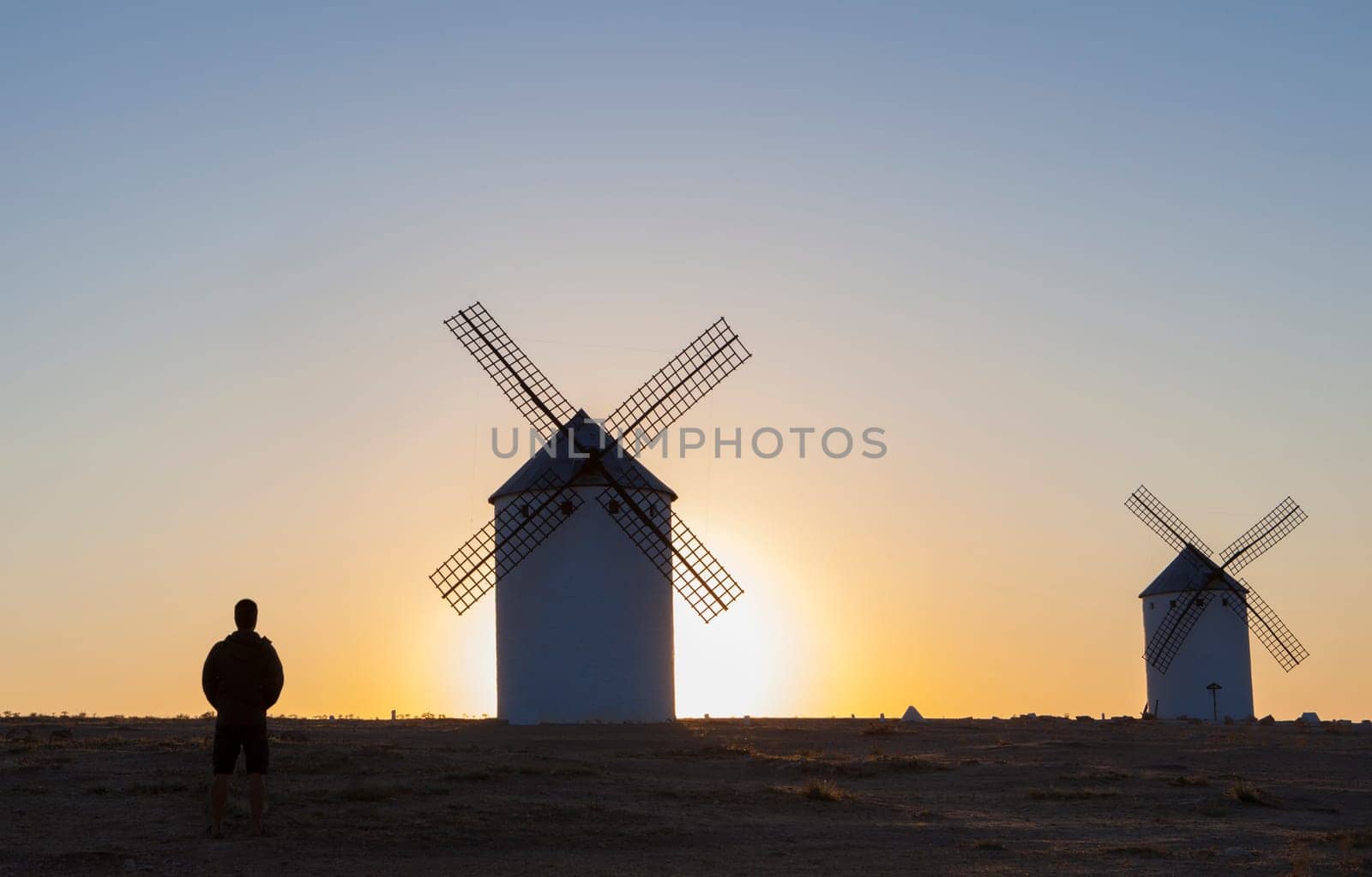 Man observing the Campo de Criptana windmills at rising through site, Spain. Ciudad Real, Spain