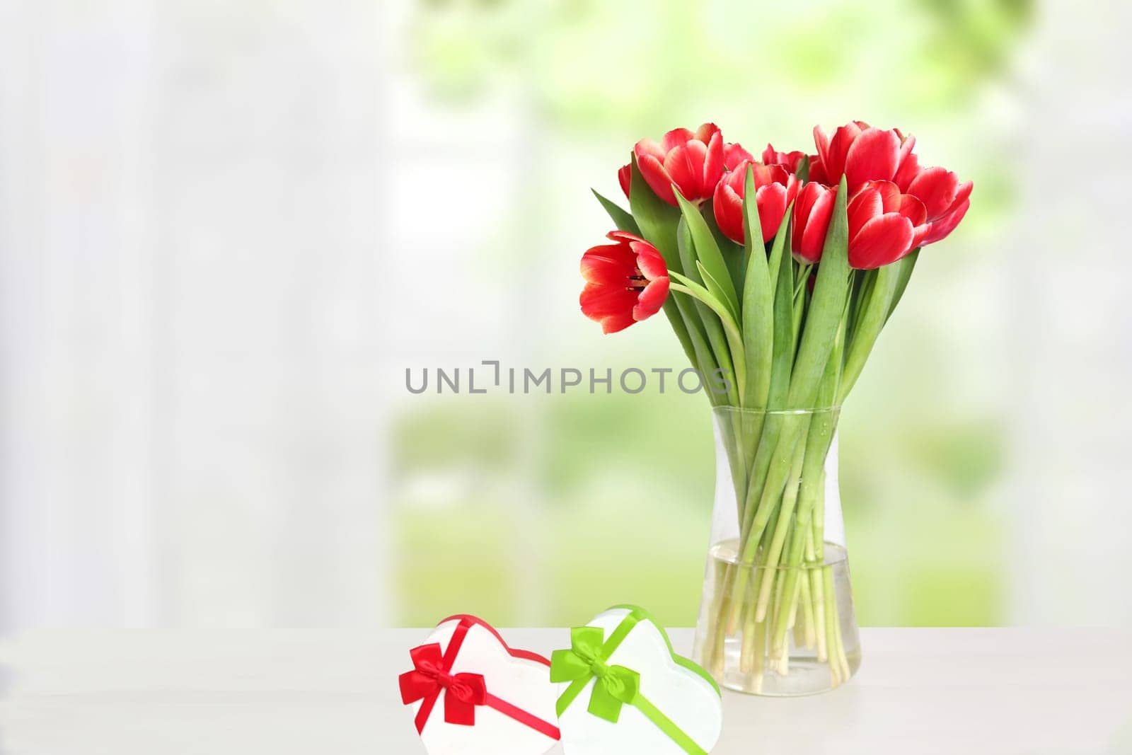Happy Valentines Day greeting card. Decorative bouquet of tulips over blurred natural background. Concept of holidays, postcard, Mothers Day, Banner and 8 March. Space.