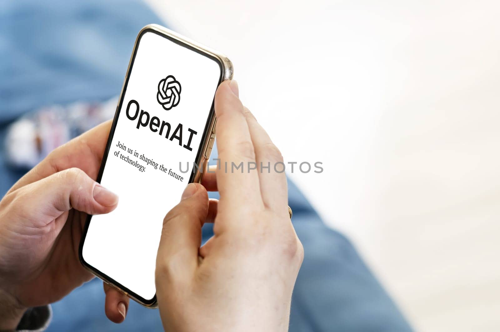 San Francisco US, Dec 2022: Female hands holding a phone with the OpenAI webpage on the screen. Interior shot. OpenAI is a non-profit artificial intelligence research organization. Technology concept