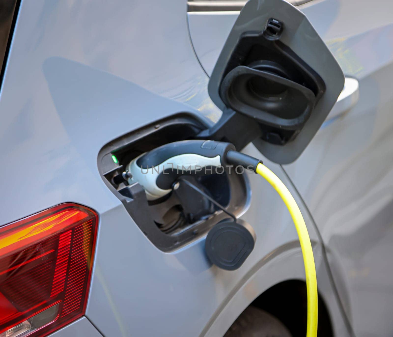 An electric car is charged at a charging station using a charging cable.