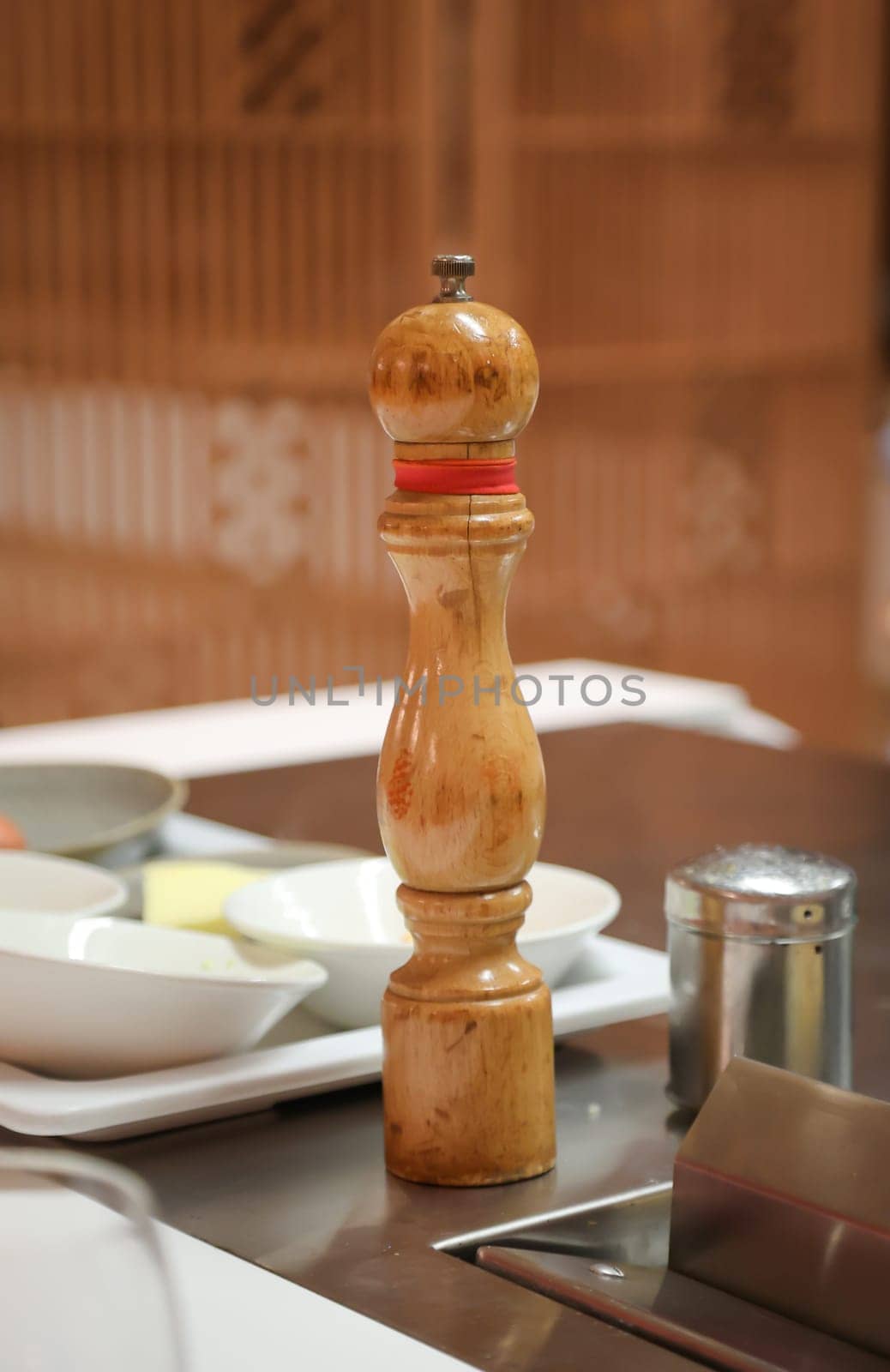 A salt or pepper mill is ready next to the stove in the kitchen.