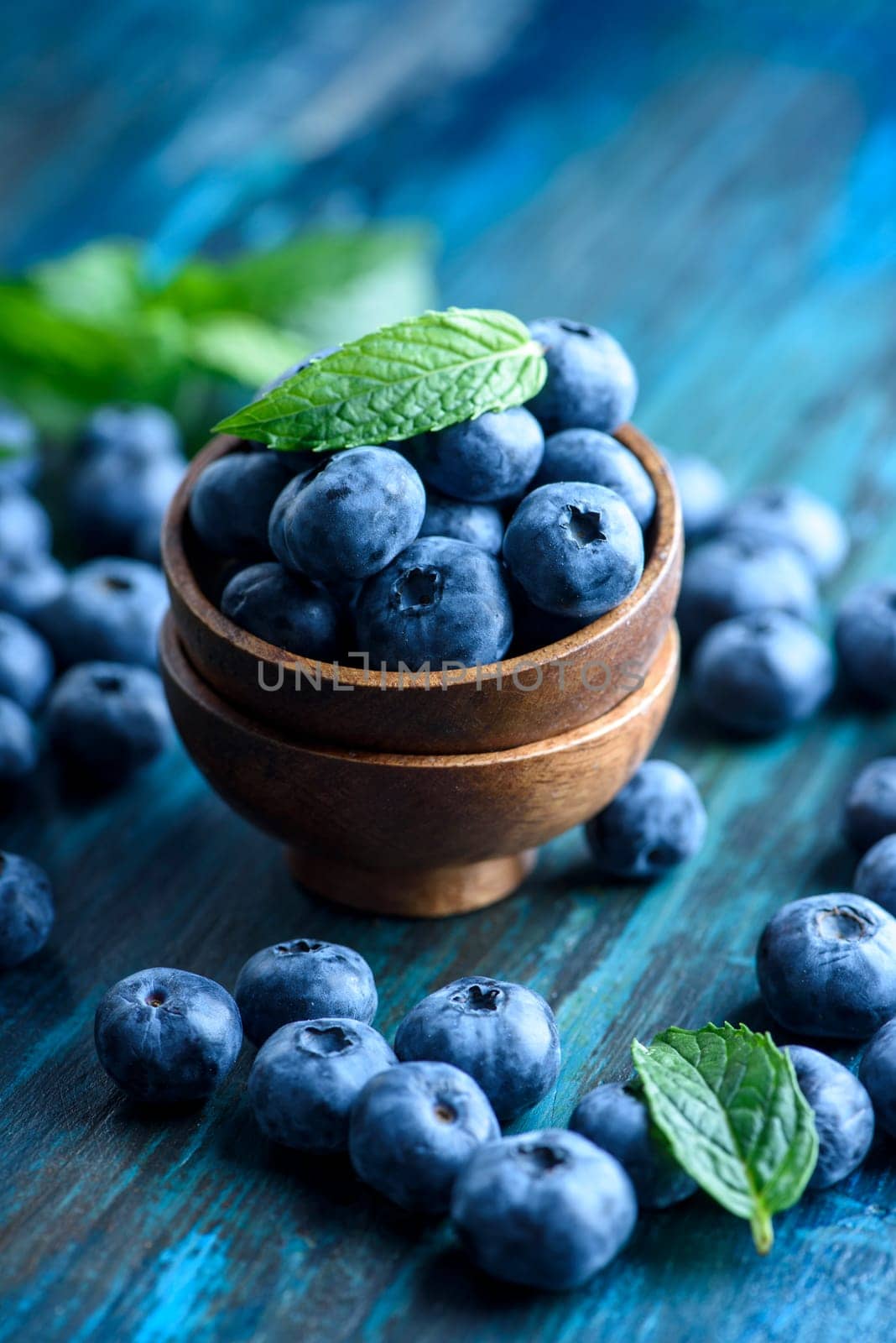 Bowl of fresh blueberries on rustic wooden table. Healthy organic seasonal fruit background. Organic food blueberries and mint leaf for healthy lifestyle.