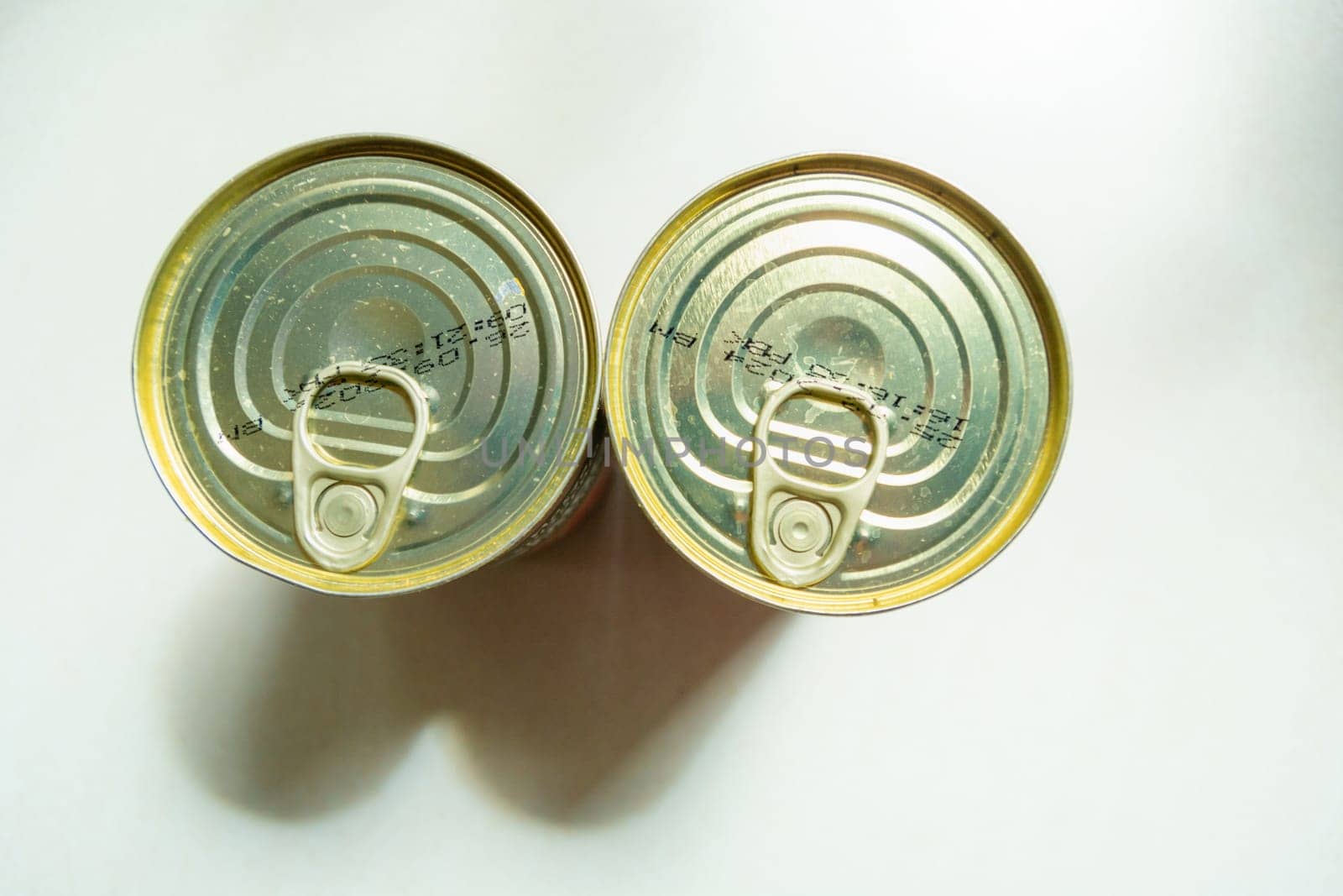 Two dirty cans with food and an opener, top view