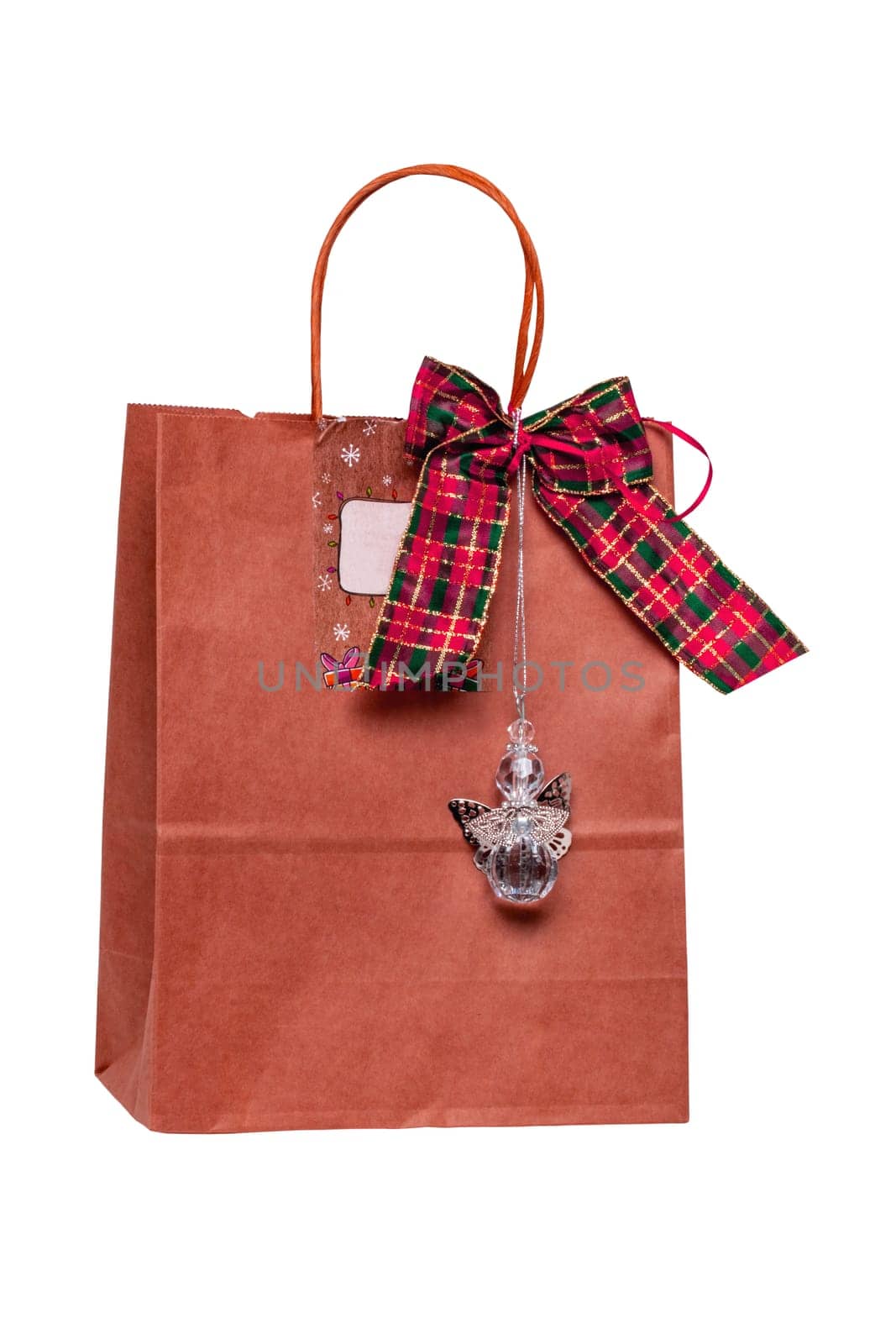 Closeup of a red paper gift bag with ribbon bow and a angel figurine isolated on a white background. Clipping path. Birthday, valentine, anniversary or other holidays.