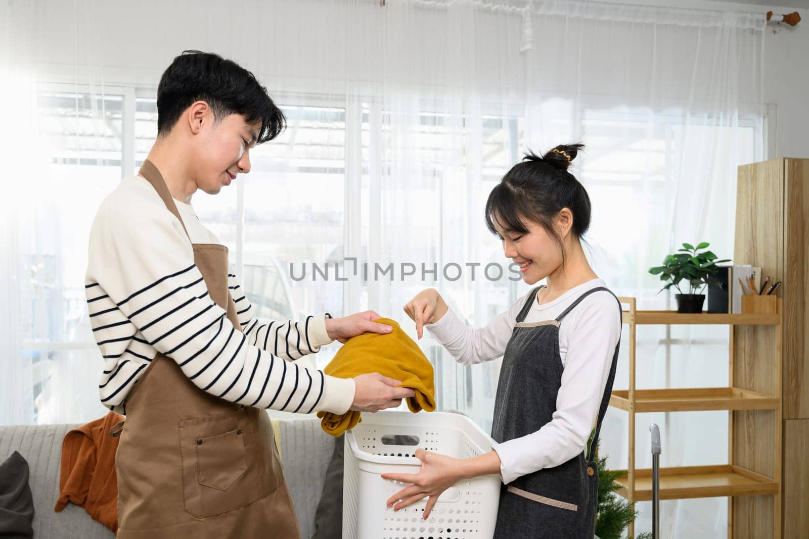 Happy asian couple enjoys tidying up their home on weekend.
