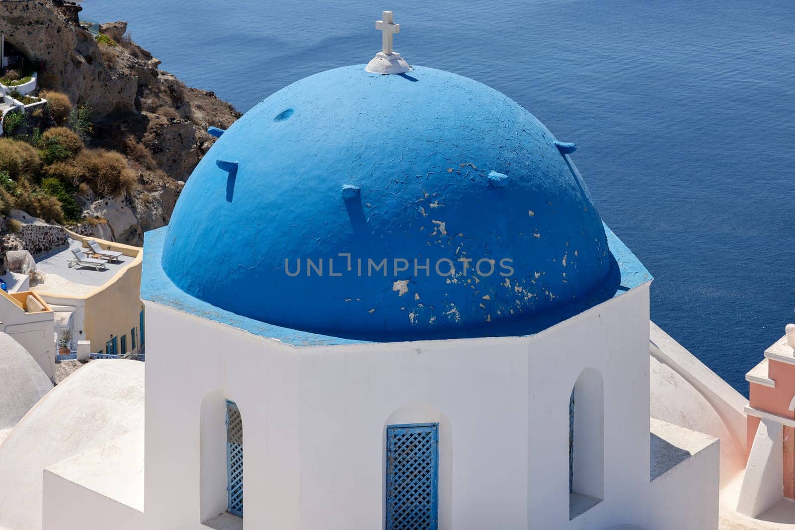 View from viewpoint of Oia village with blue dome of  greek orthodox Christian church. Santorini, Greece