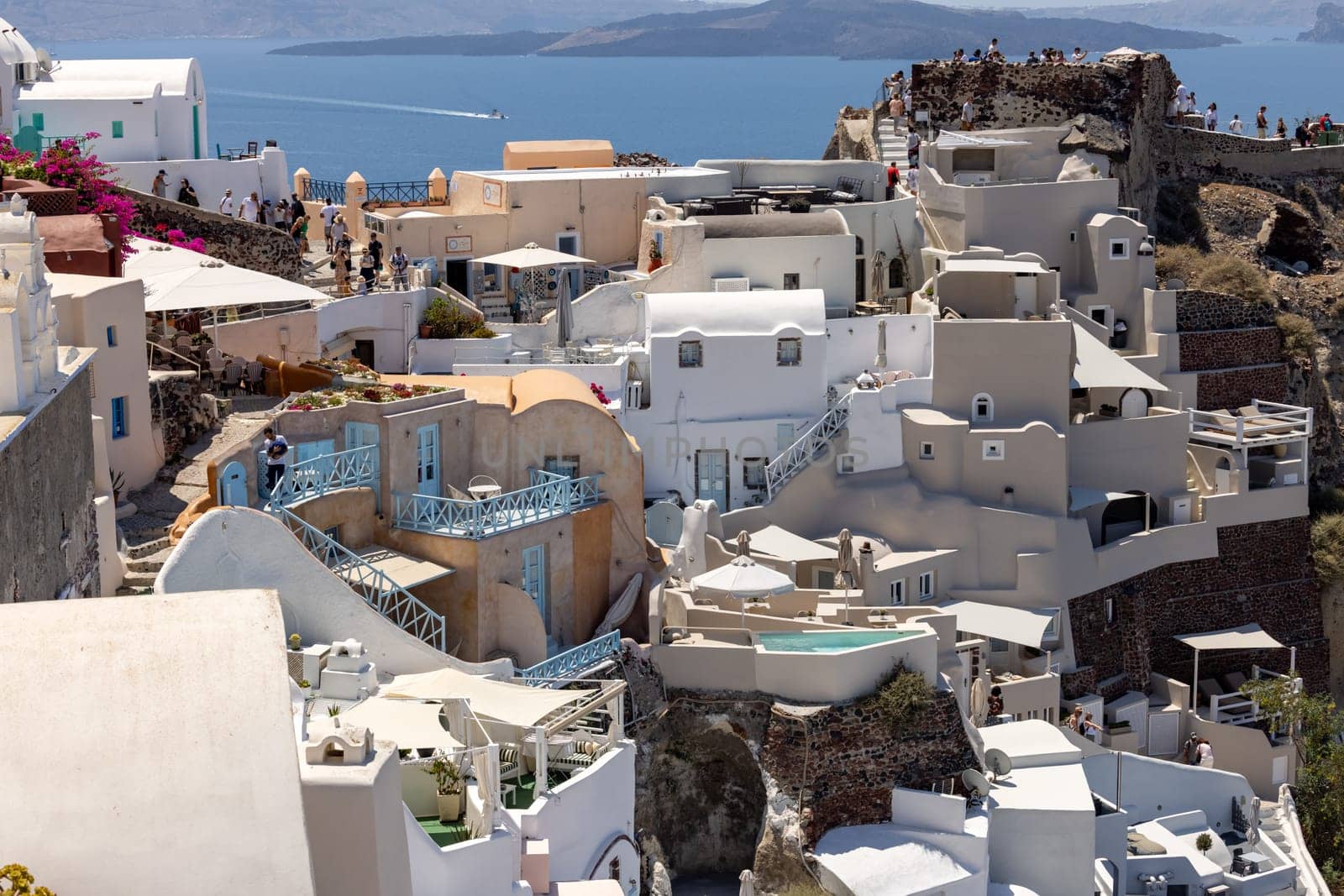 Oia, Santorini, Greece - July 3, 2021: Whitewashed houses with terraces and pools and a beautiful view in Oia on Santorini island, Greece