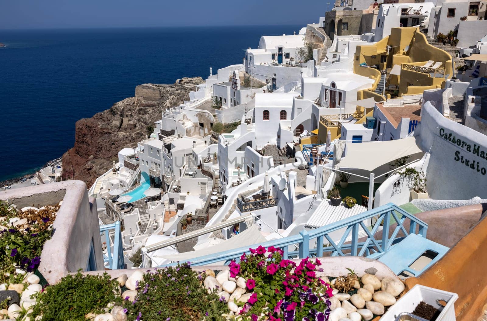 Oia, Santorini, Greece - July 3, 2021: Whitewashed houses with terraces and pools and a beautiful view in Oia on Santorini island, Greece