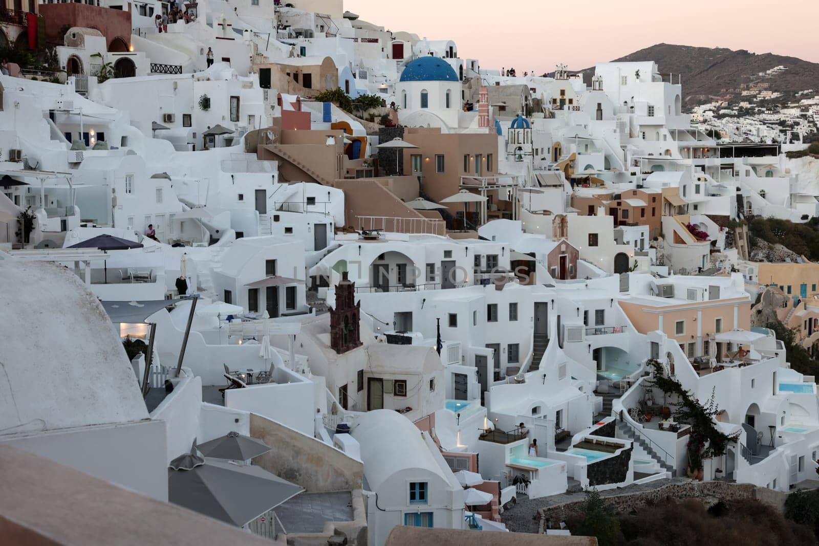 Oia, Santorini, Greece - June 28, 2021: Whitewashed houses with terraces and pools and a beautiful view in Oia on Santorini island, Greece