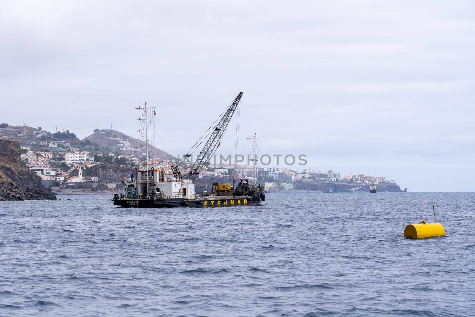 Madeira / Portugal - July 15, 2021. The industrial ship with workers moored at Madeira coast.