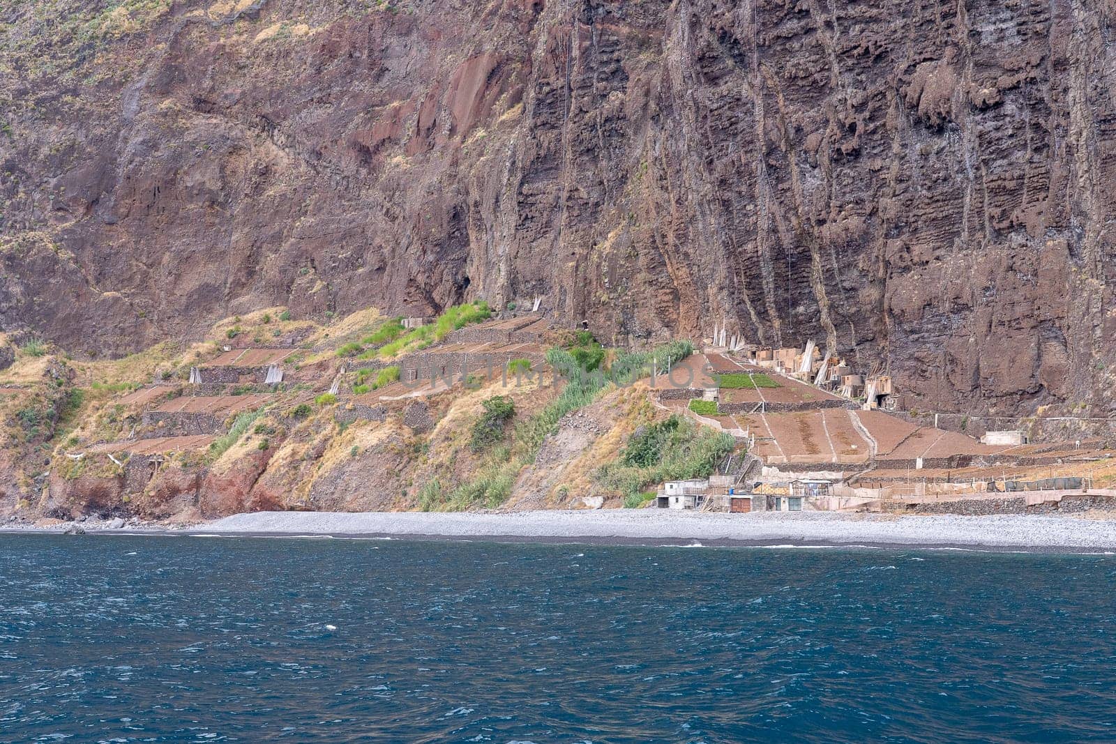 View of sheer volcanic cliff rising above ocean.