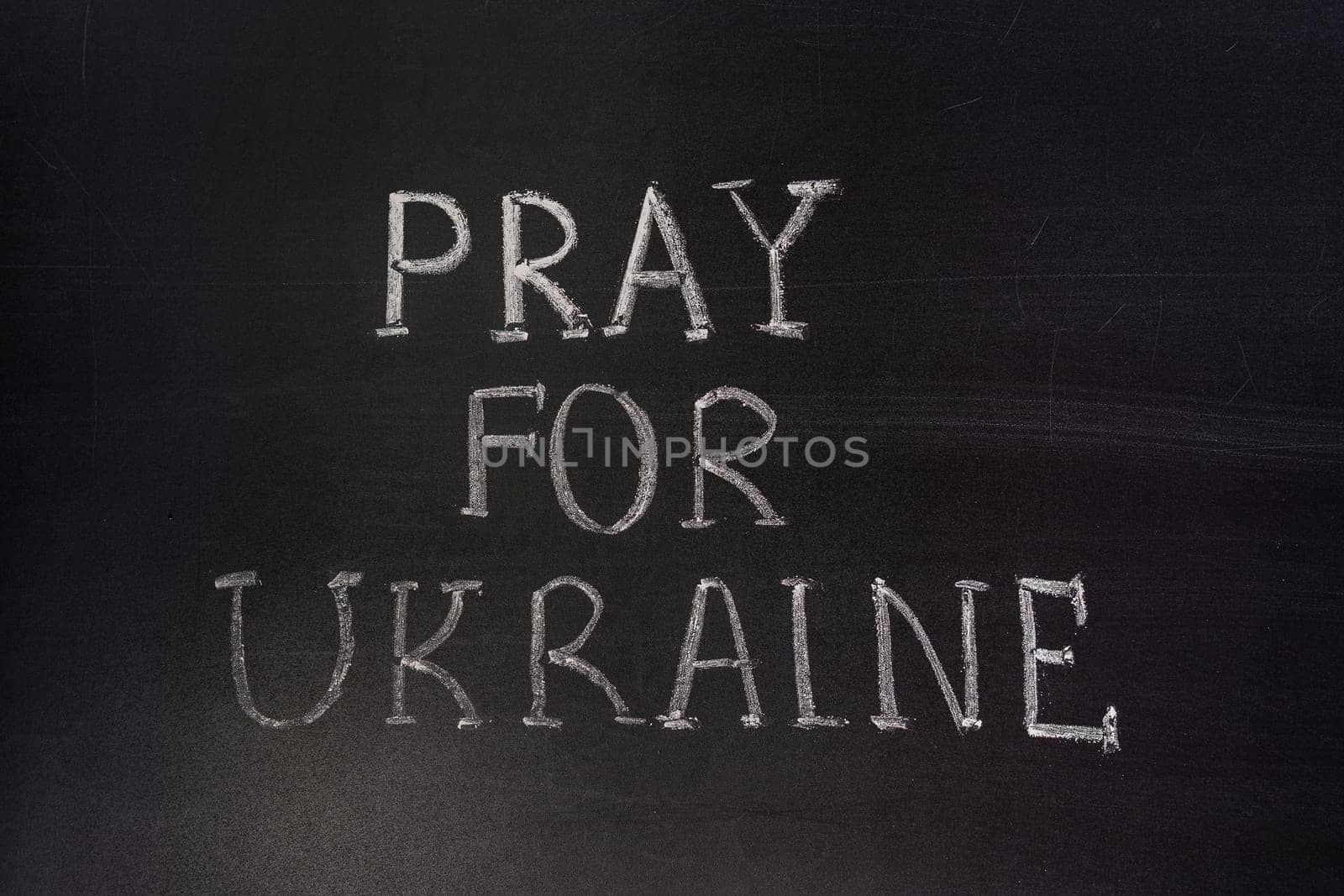 Words "Pray for Ukraine"" writed on blackboard with chalk"