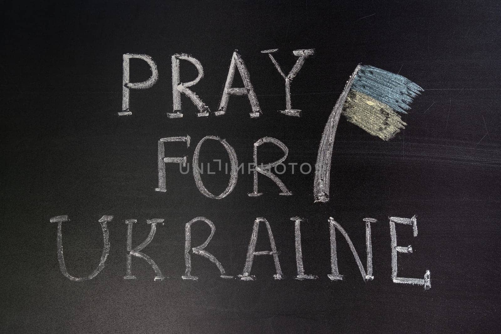 Words "Pray for Ukraine"" writed on blackboard with chalk"