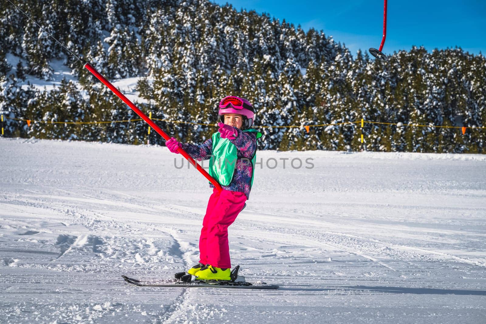 Young skier, a child, having fun when riding up on a ski drag lift. Winter holidays in El Tarter, Andorra, Pyrenees Mountains, Grandvalira