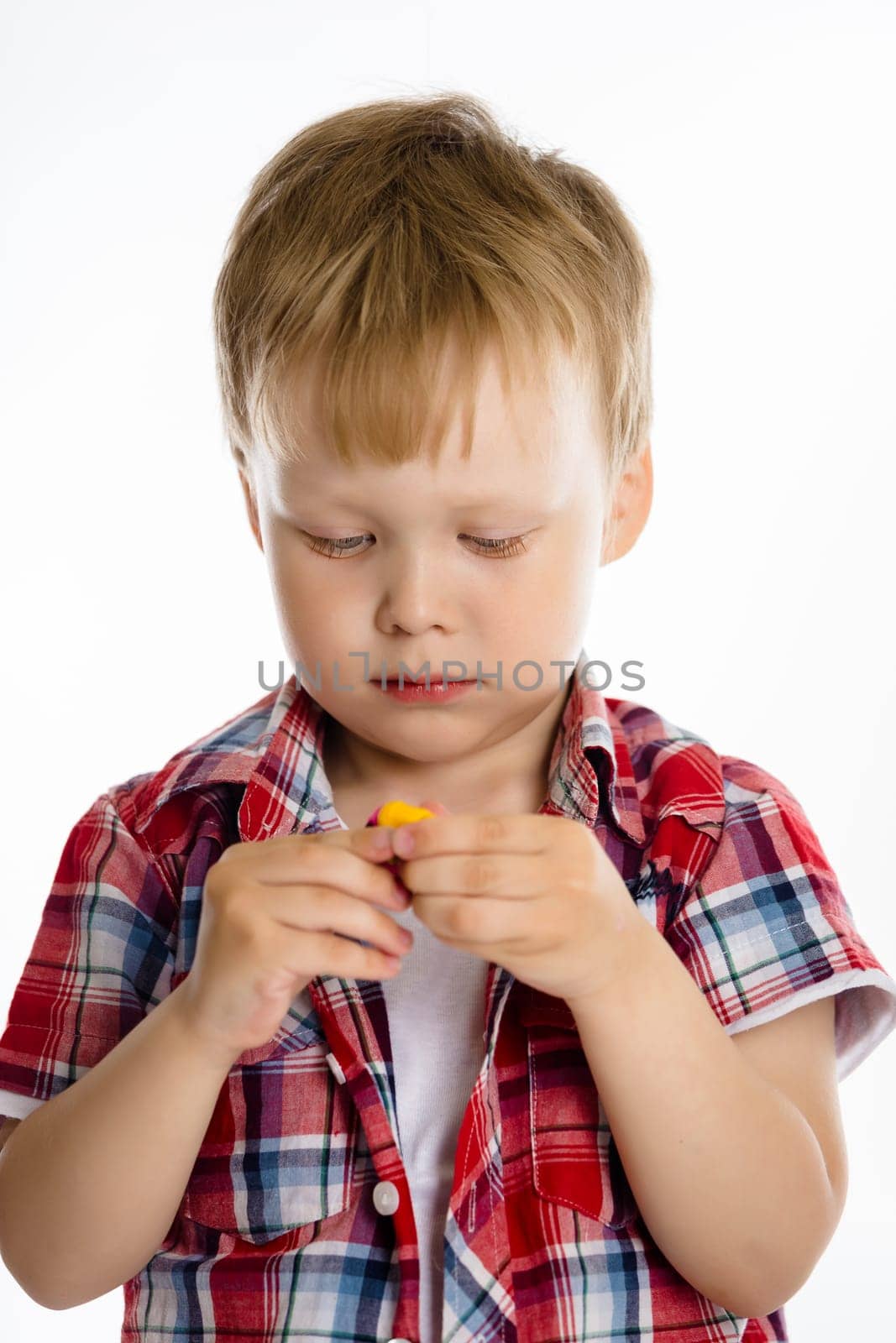 Little boy standing playing with toy. studio