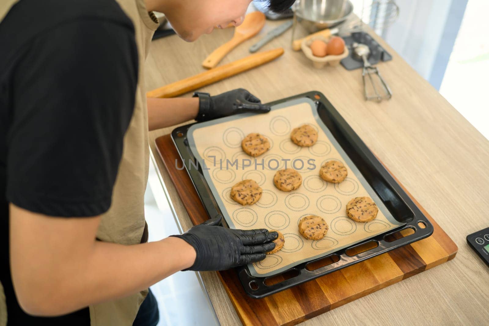 Home baker arranging a tray of chocolate chip cookie dough before baking.