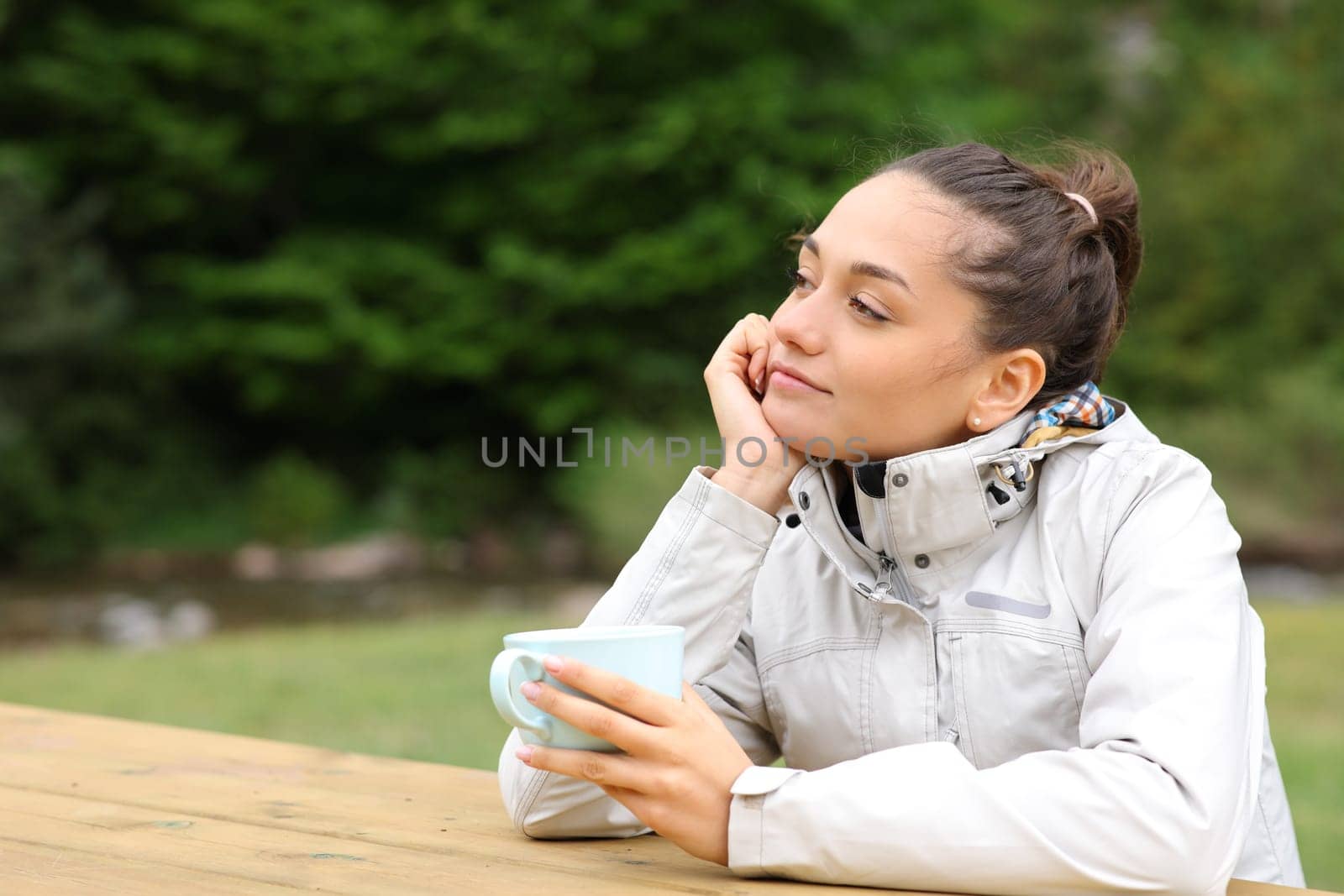 Hiker thinking holding coffee cup in a camping table