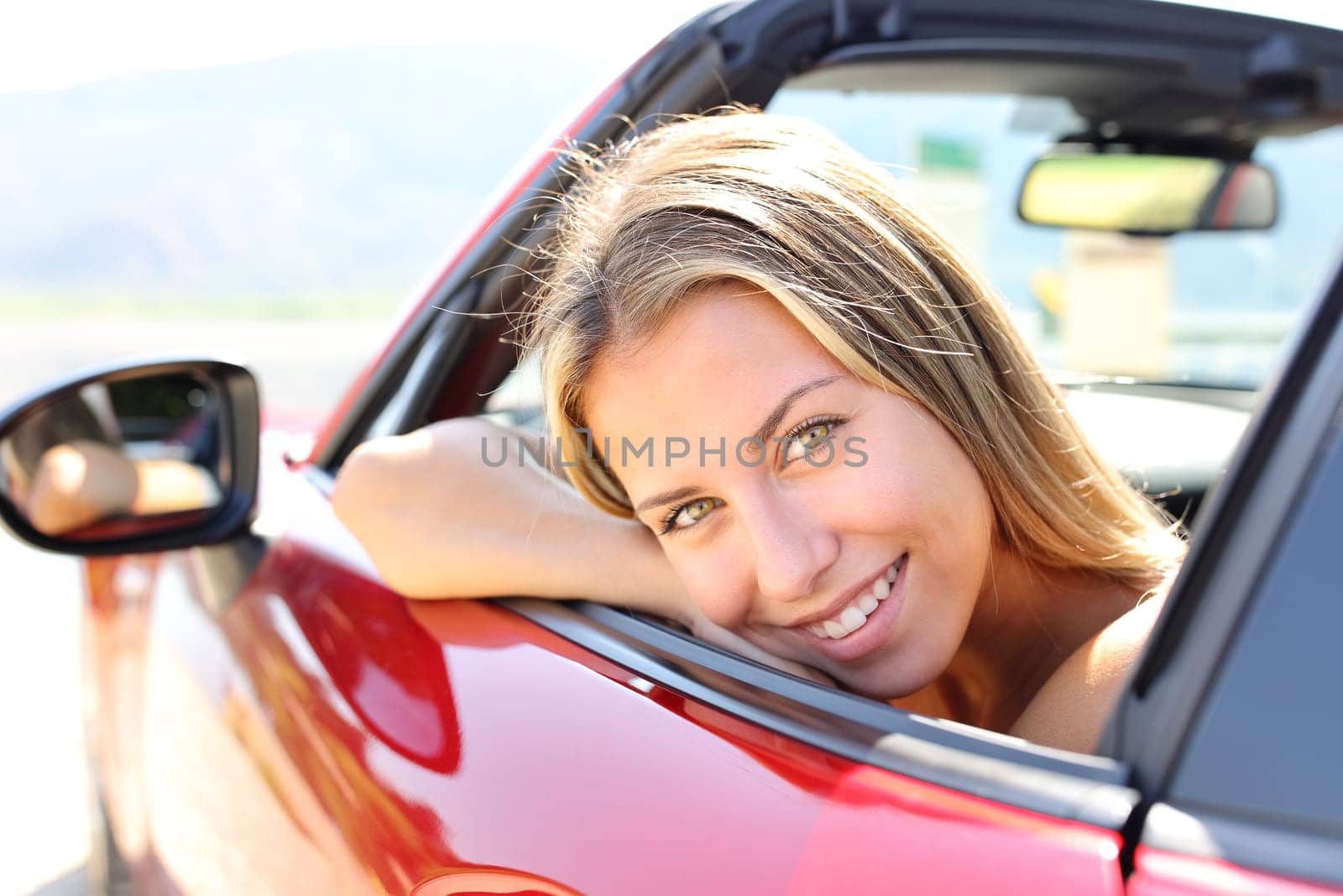 Happy convertible car driver looks at you smiling