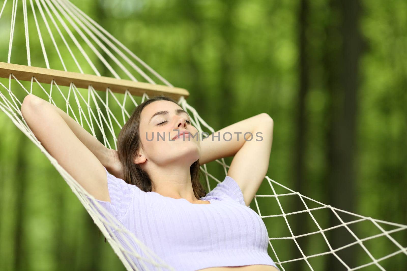 Woman resting and relaxing lying on hammock in a forest