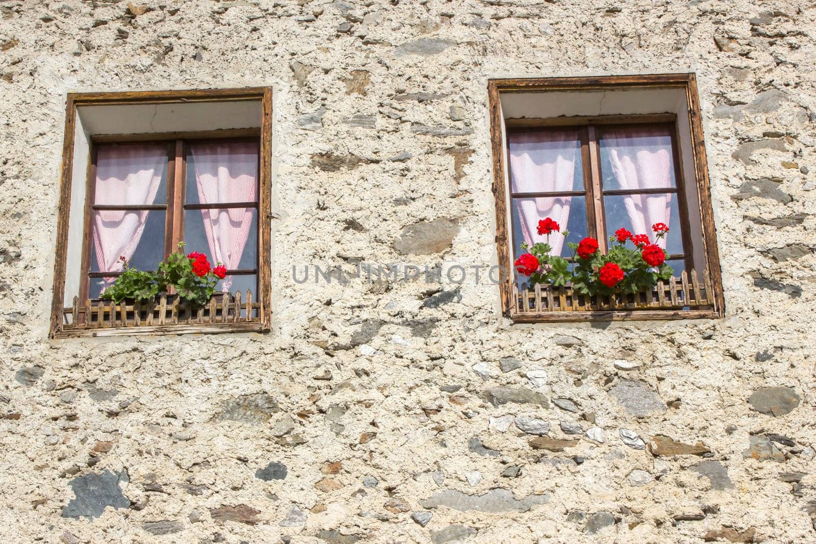Old building with red flowers in windows - facade with old window, Austria