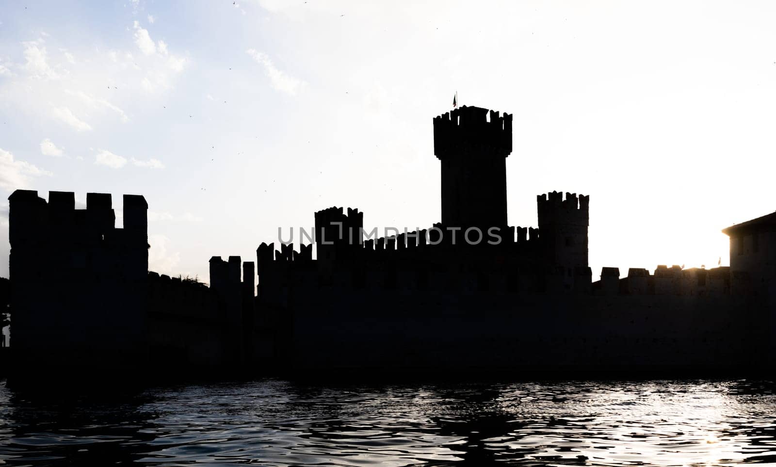 Italy - Sirmone castle silhouette on the Garda lake at sunset. Medieval architecture with tower