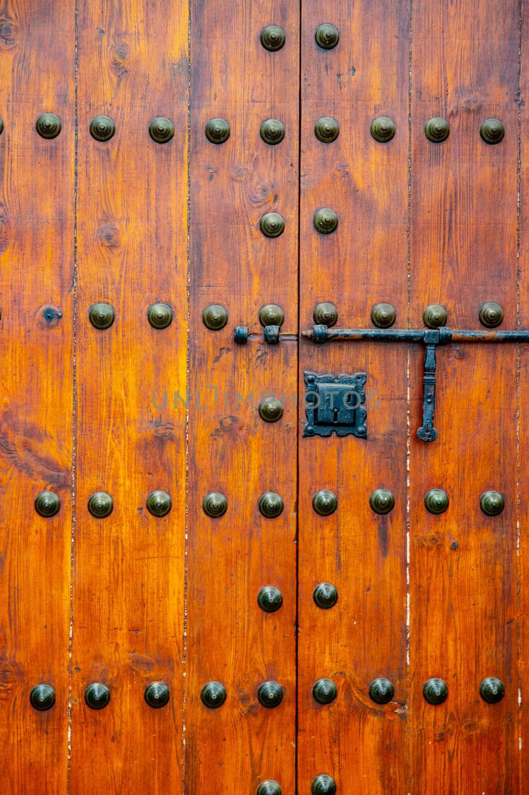 Detail from old massive large wooden door in a stone wall of a church.