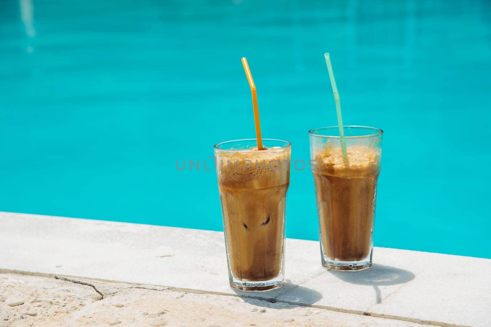 Two glass of iced frappe near the swimming pool.
