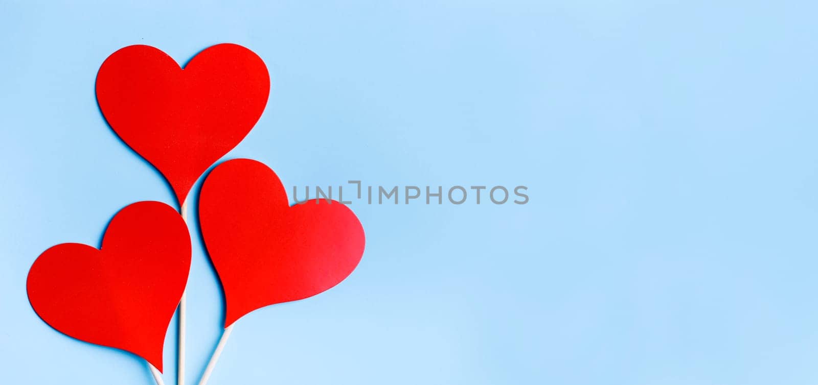Red valentine hearts on pastel blue background from above. Valentine's day celebration banner. Creative minimal love concept. Hearts balloons top view. Valentine pop art colorful simple design layout.