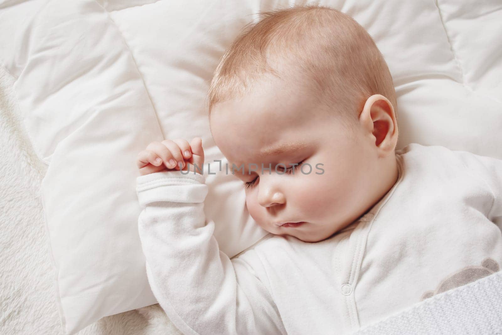Cute five month old baby sleeping in comfortable bed. Concept of the family andparenting.