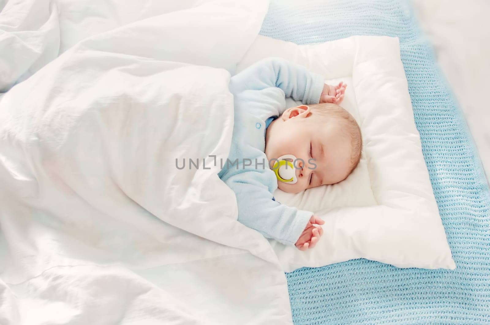 Cute three month old baby sleeping in comfortable bed. Concept of the family andparenting.