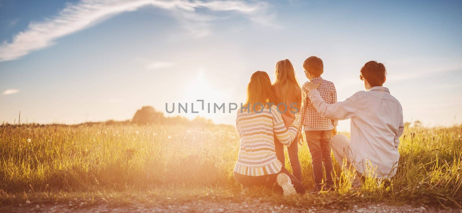 Family standing on the sunset on the field in natural park. Concept of the relationship between people and vacation together.