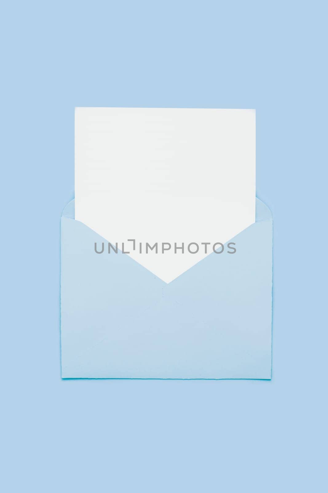 Closeup on blank empty white paper card in blue opened envelope isolated on blue pastel color background. Love letter minimal concept. Conceptual layout template with text place on postcard. Mock-up