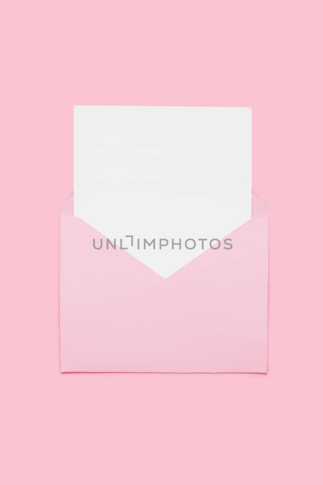 Closeup on blank empty white paper card in pink opened envelope isolated on pink pastel color background. Love letter minimal concept. Conceptual layout template with text place on postcard. Mock-up