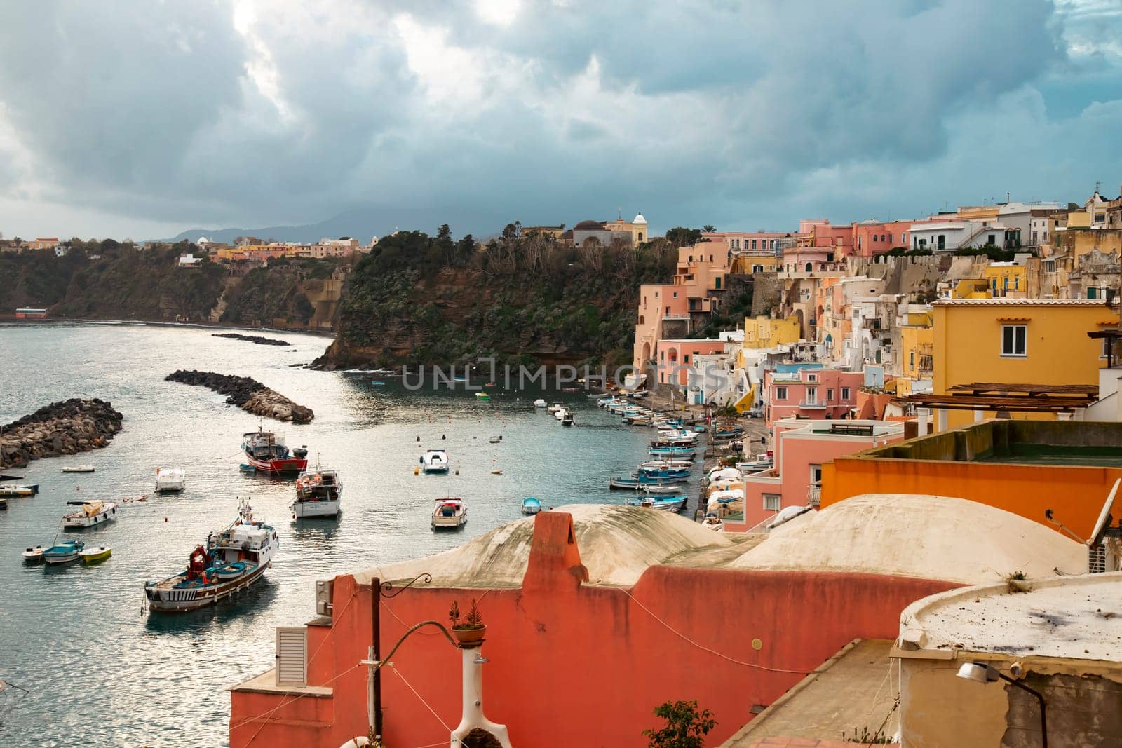 View of the Port of Corricella with lots of colorful houses on a sunny day in Procida Island, Italy.