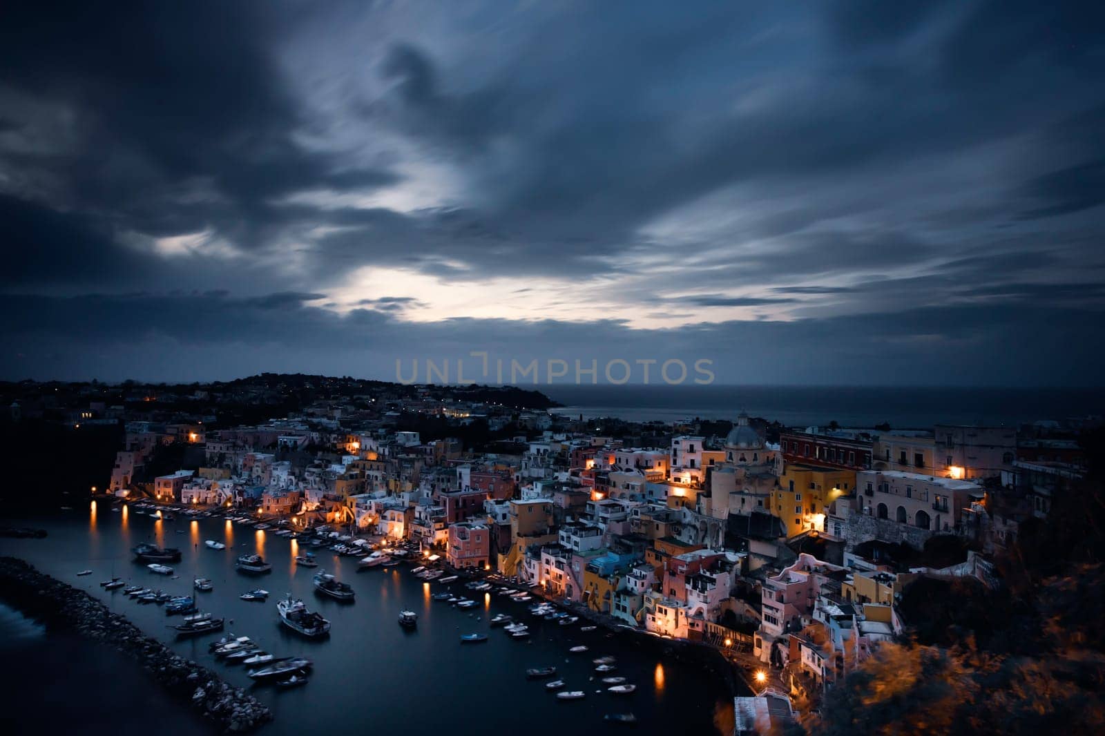 View of the Port of Corricella with lots of colorful houses after sunset in Procida Island, Italy.
